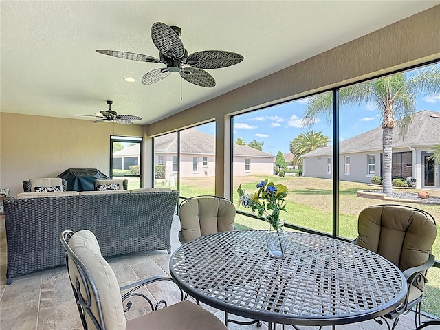 sunroom featuring ceiling fan, a residential view, and outdoor dining space