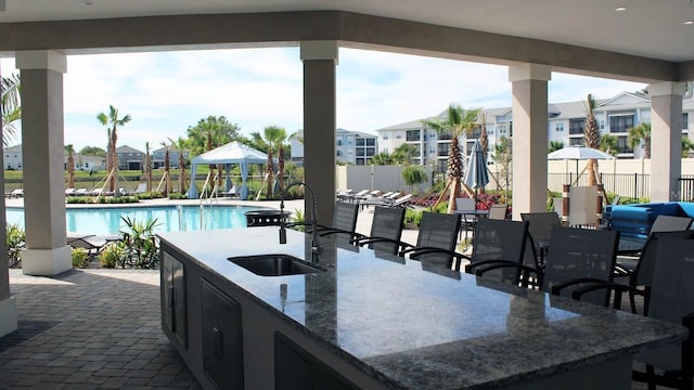 view of patio with a residential view, a sink, a gazebo, fence, and a community pool