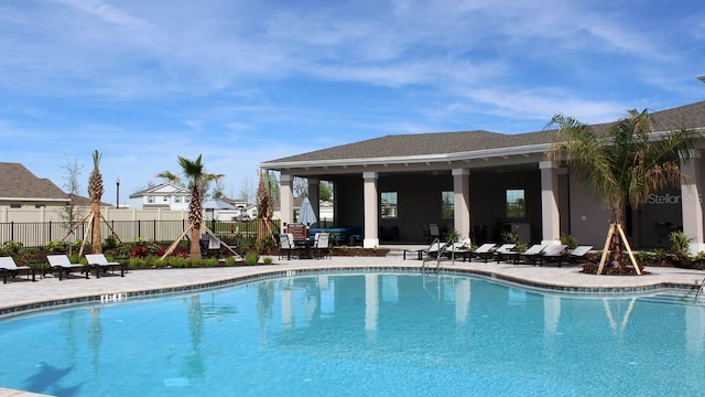 community pool with a patio and fence
