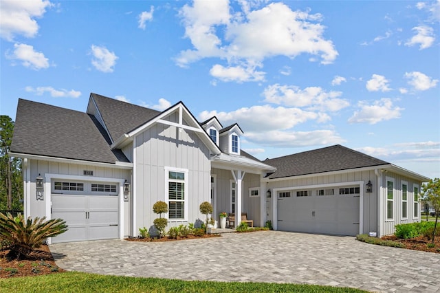view of front of house featuring an attached garage, decorative driveway, board and batten siding, and a shingled roof