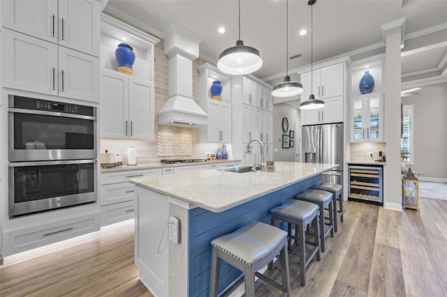 kitchen with beverage cooler, stainless steel appliances, a sink, crown molding, and light wood-style flooring