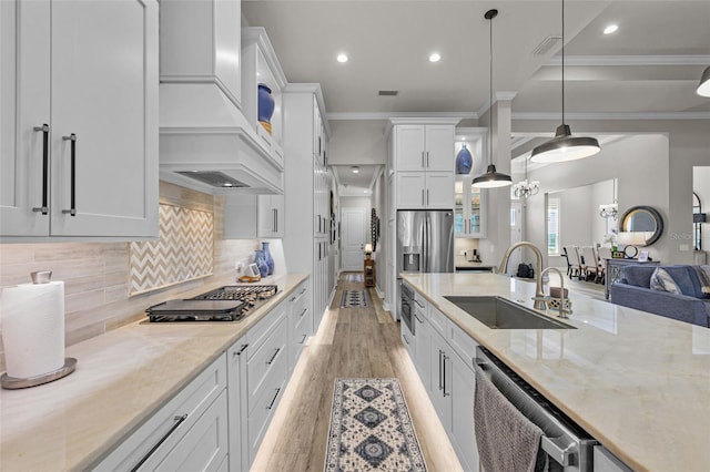 kitchen with custom exhaust hood, a sink, appliances with stainless steel finishes, and crown molding