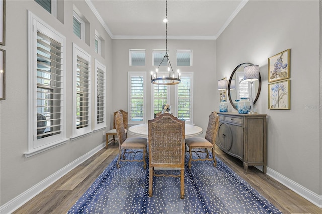 dining area with ornamental molding, wood finished floors, and a chandelier