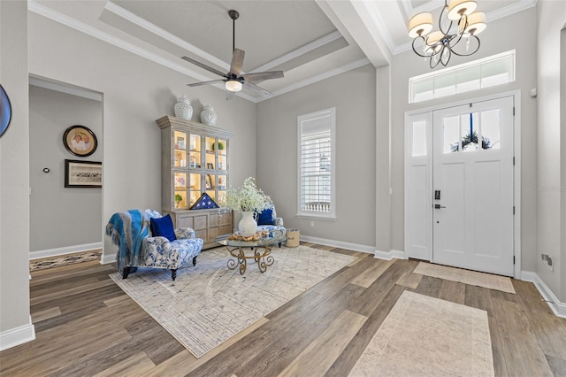 foyer entrance featuring baseboards, ornamental molding, wood finished floors, and ceiling fan with notable chandelier