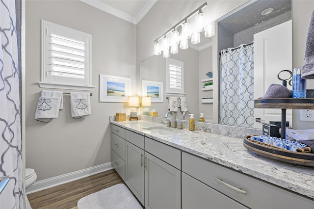 bathroom featuring toilet, baseboards, wood finished floors, vanity, and ornamental molding