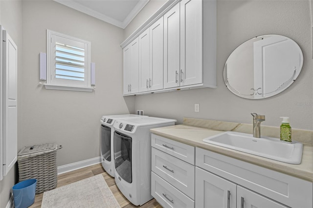 laundry room with washer and clothes dryer, a sink, crown molding, cabinet space, and light wood-style flooring