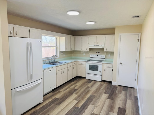 kitchen featuring a sink, under cabinet range hood, white appliances, visible vents, and light countertops