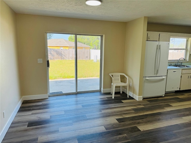 dining space with a textured ceiling, dark wood-style flooring, a healthy amount of sunlight, and baseboards