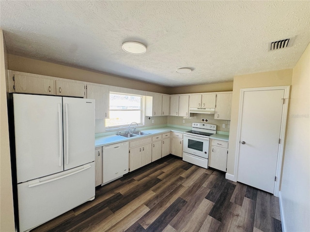 kitchen with a sink, under cabinet range hood, white appliances, light countertops, and a textured ceiling