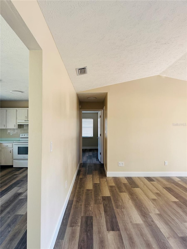 corridor with lofted ceiling, a textured ceiling, visible vents, baseboards, and dark wood-style flooring