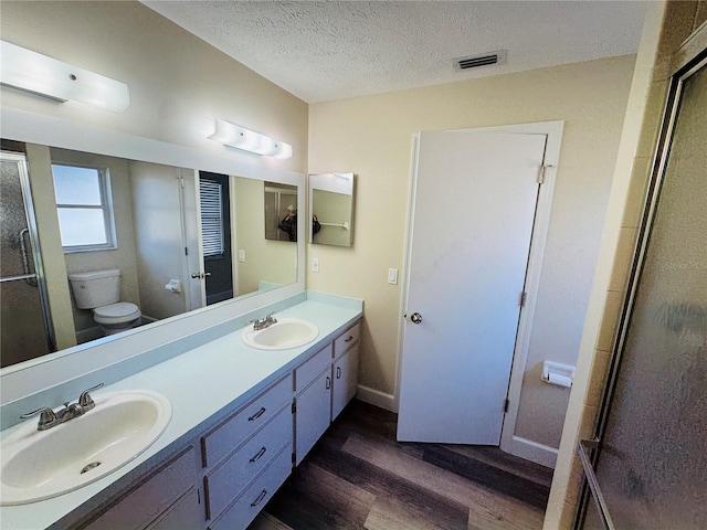 full bath featuring toilet, a sink, wood finished floors, and visible vents