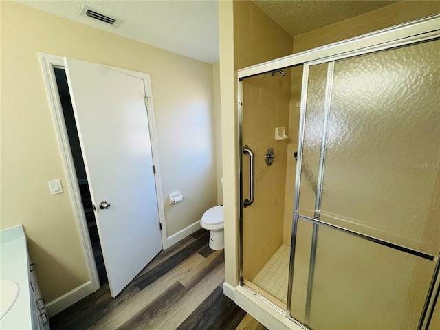 full bathroom featuring toilet, a stall shower, visible vents, baseboards, and wood finished floors