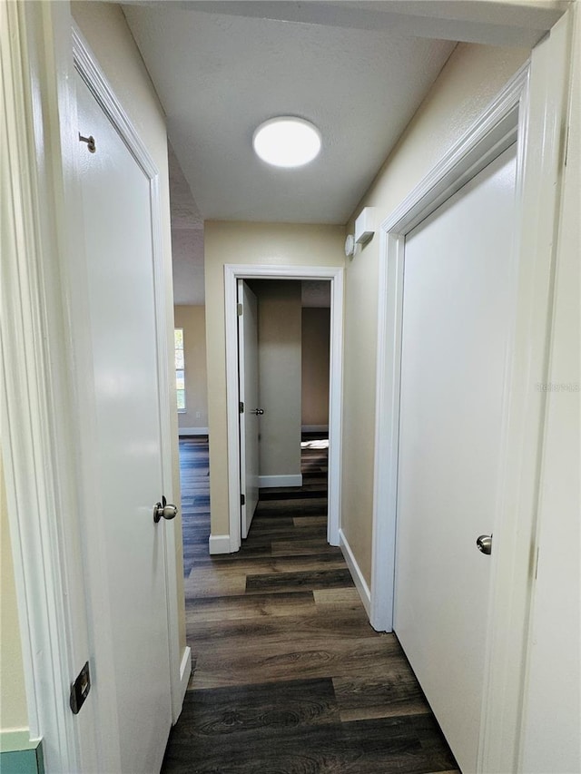 corridor with dark wood finished floors and baseboards