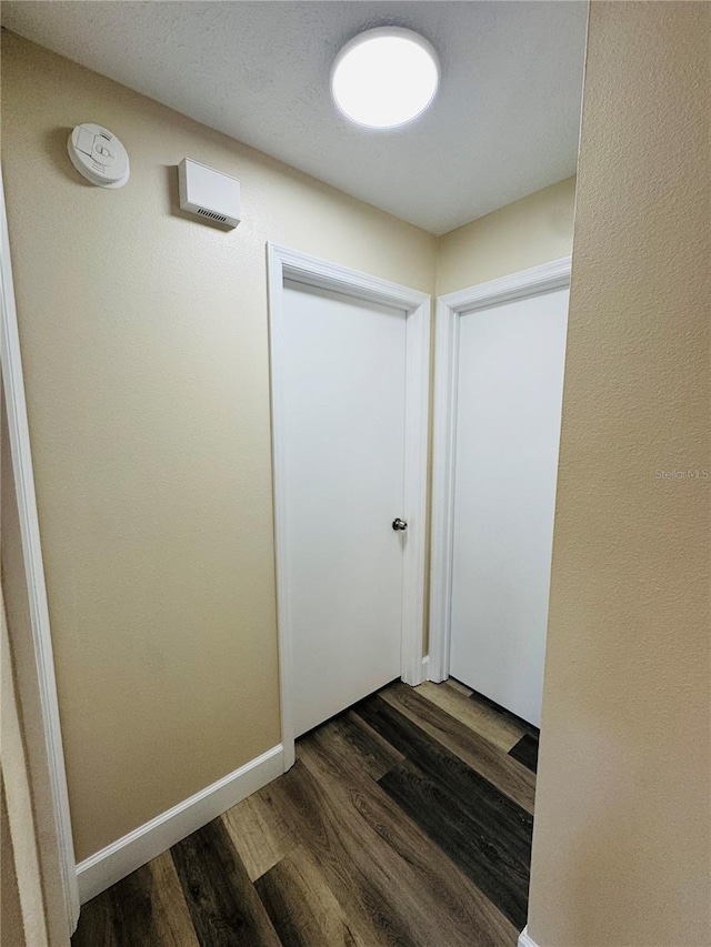 hall featuring baseboards and dark wood-type flooring
