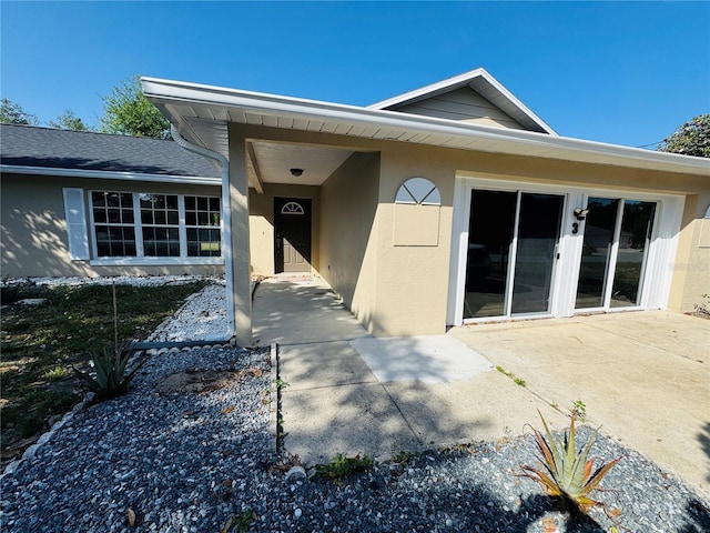 property entrance with stucco siding and a patio