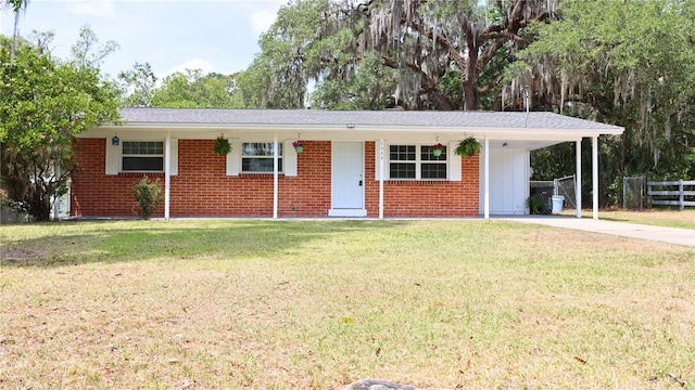 ranch-style home featuring a front lawn, an attached carport, driveway, brick siding, and fence