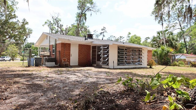 rear view of property featuring fence, a chimney, and brick siding