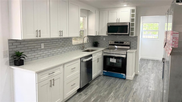 kitchen featuring white cabinets, appliances with stainless steel finishes, decorative backsplash, and a sink