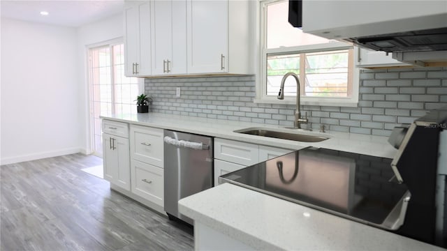 kitchen featuring tasteful backsplash, stainless steel dishwasher, white cabinets, and a sink