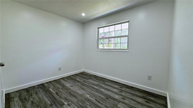 unfurnished room with a textured ceiling, dark wood-style flooring, and baseboards