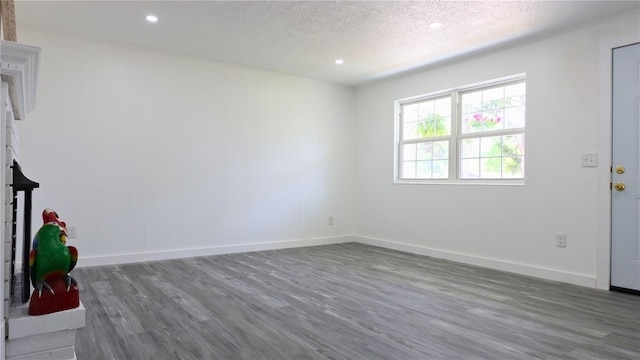 interior space featuring baseboards, recessed lighting, wood finished floors, and a textured ceiling