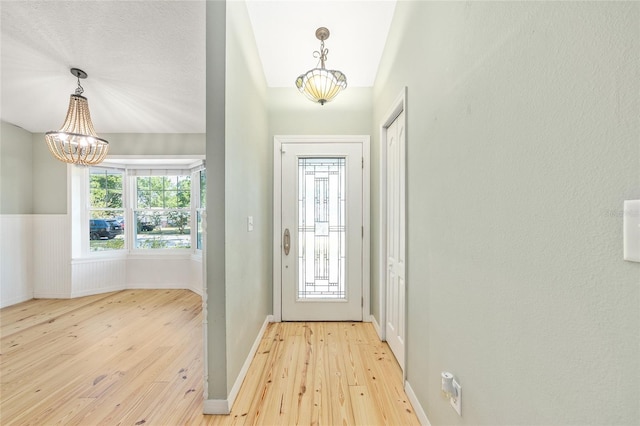8 Banyan Dr, Ocala, FL 34472 - doorway to outside with baseboards, light wood-style flooring, and a notable chandelier
