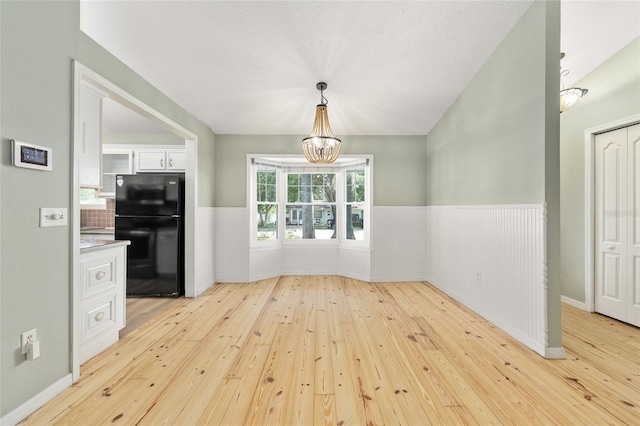 8 Banyan Dr, Ocala, FL 34472 - unfurnished dining area with an inviting chandelier, wainscoting, and light wood finished floors