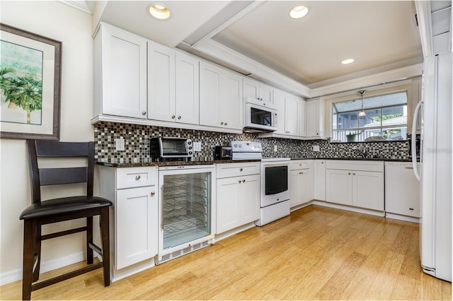 255 NW Bay Path Dr, Crystal River, FL 34428 - kitchen with decorative backsplash, wine cooler, white appliances, light wood-type flooring, and white cabinetry