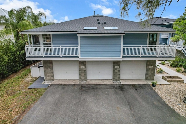 255 NW Bay Path Dr, Crystal River, FL 34428 - rear view of house with an attached garage, a shingled roof, a balcony, and stone siding