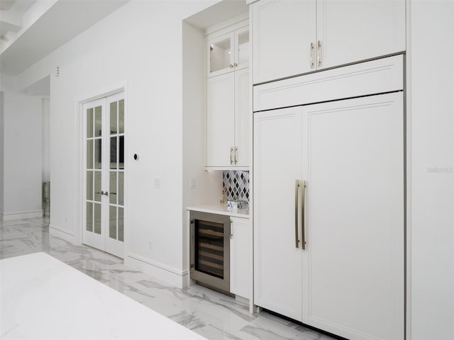 bar with paneled refrigerator, marble finish floor, a bar, french doors, and wine cooler