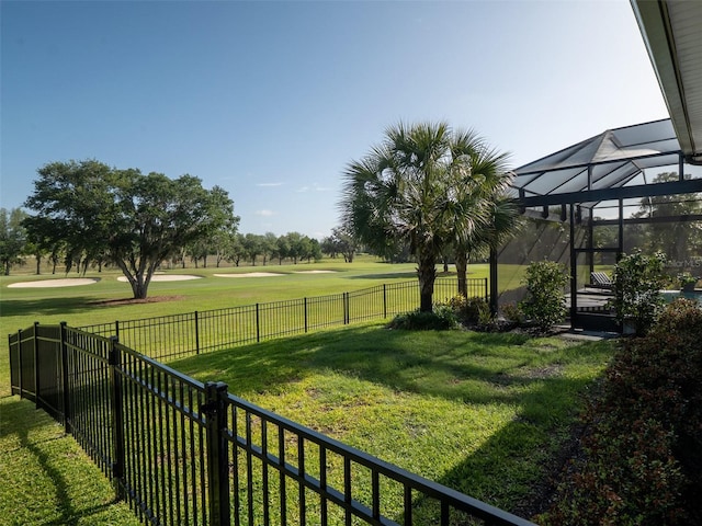 view of yard featuring glass enclosure, a fenced backyard, and golf course view