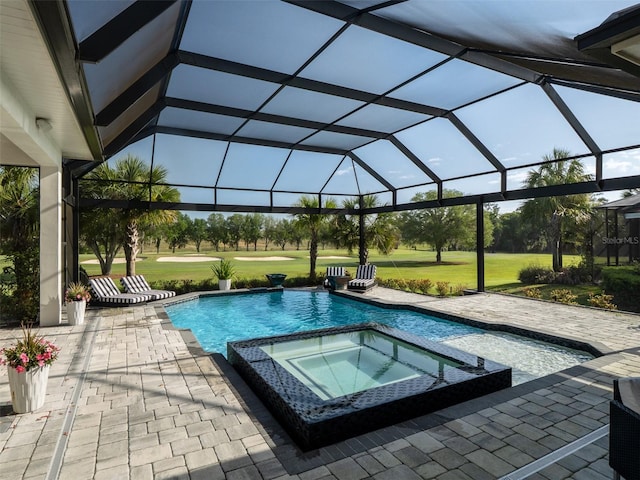 view of swimming pool featuring a pool with connected hot tub, glass enclosure, a yard, and a patio area