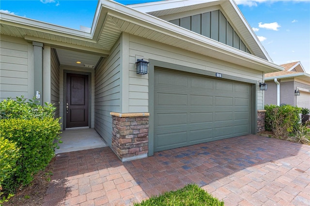 exterior space featuring decorative driveway, stone siding, board and batten siding, and a garage