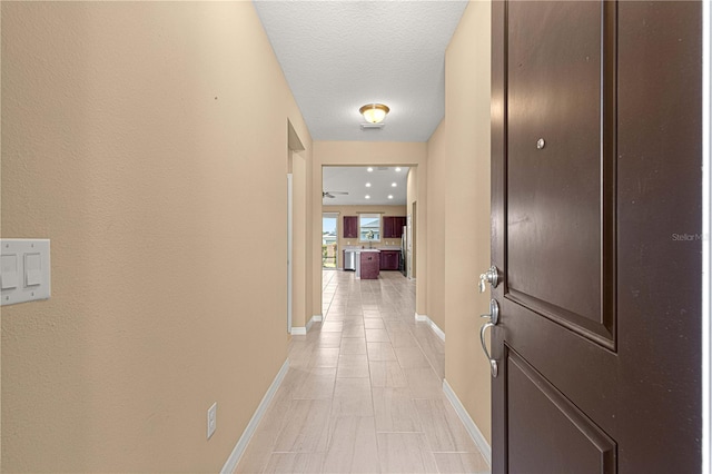 hall with light tile patterned flooring and baseboards