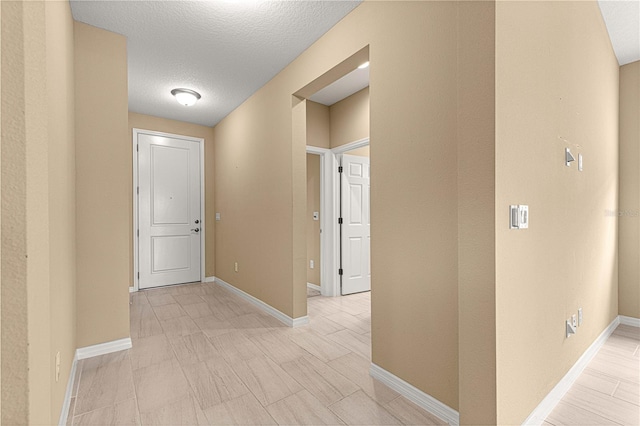 hallway featuring a textured ceiling and baseboards