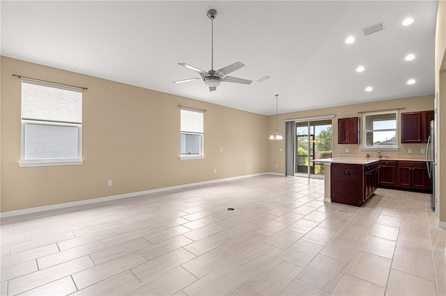 kitchen featuring visible vents, light countertops, open floor plan, vaulted ceiling, and a ceiling fan