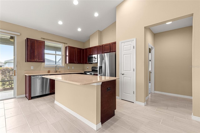 kitchen with a sink, a center island, light countertops, appliances with stainless steel finishes, and lofted ceiling