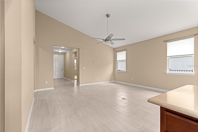 unfurnished dining area featuring a ceiling fan, high vaulted ceiling, and baseboards