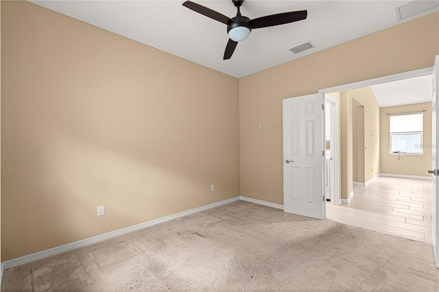 empty room featuring baseboards, visible vents, a ceiling fan, and light colored carpet