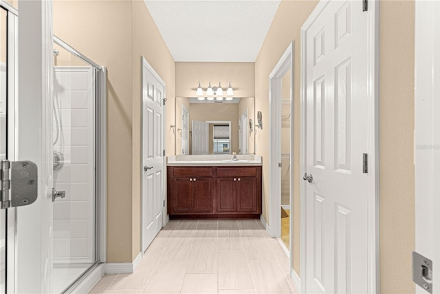 bathroom with a stall shower, vanity, and baseboards