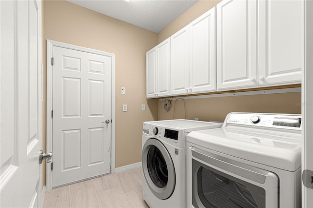 laundry room featuring separate washer and dryer, cabinet space, and baseboards