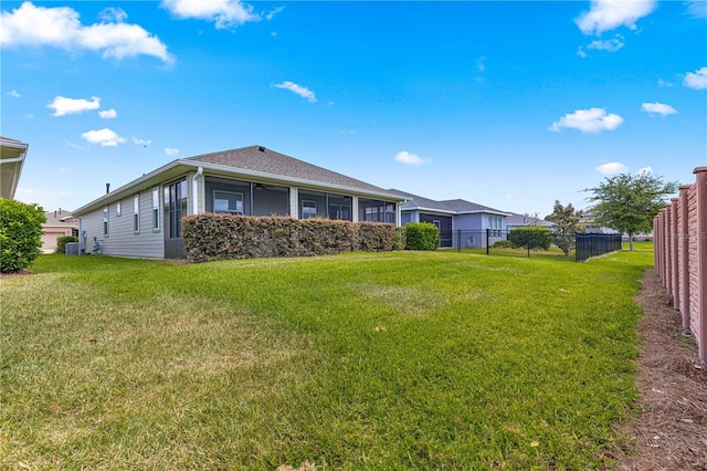 rear view of house featuring fence, a yard, and a sunroom