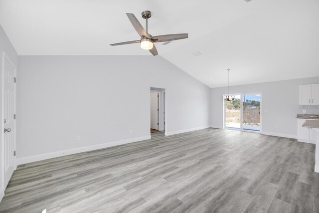 13493 SW 112th Pl, Dunnellon, FL 34432 - unfurnished living room with a ceiling fan, vaulted ceiling, light wood-style floors, baseboards, and a chandelier
