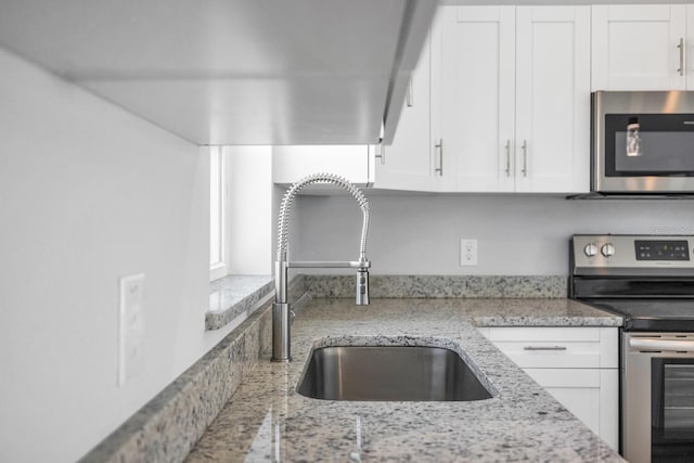 13493 SW 112th Pl, Dunnellon, FL 34432 - kitchen with stainless steel appliances, a sink, white cabinets, and light stone countertops