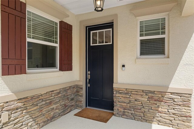 9923 SW 98th Ln, Ocala, FL 34481 - doorway to property featuring stone siding, stucco siding, and covered porch