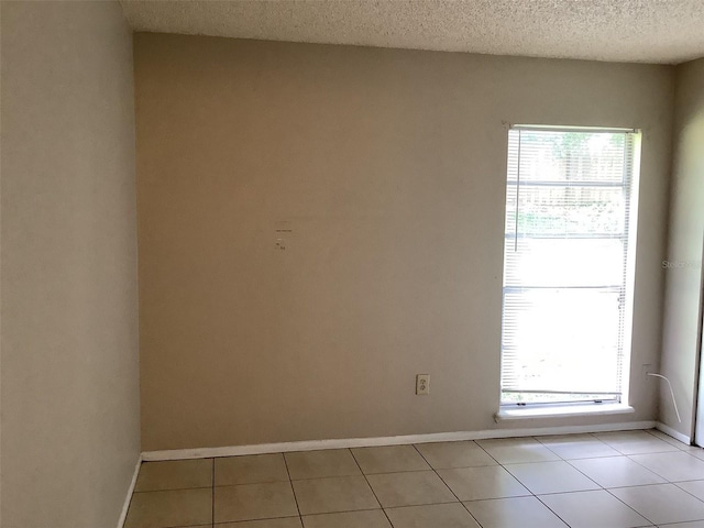 5440 SE 30th Pl, Ocala, FL 34480 - spare room featuring light tile patterned floors, baseboards, a textured ceiling, and a wealth of natural light