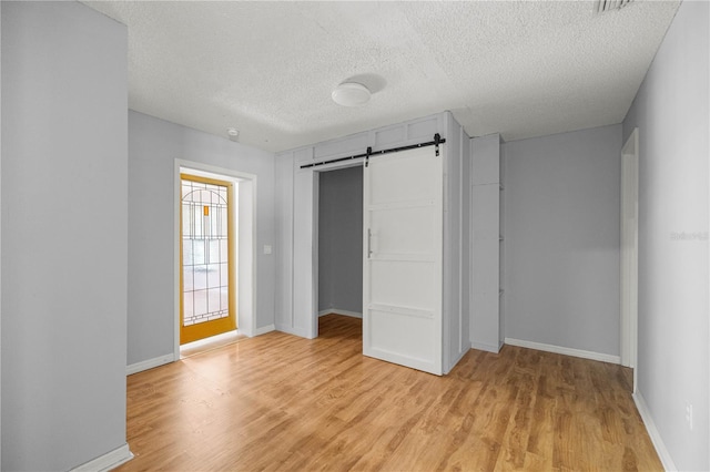14171 SW 8th Ave, Ocala, FL 34473 - unfurnished bedroom with a barn door, light wood finished floors, a textured ceiling, and a closet