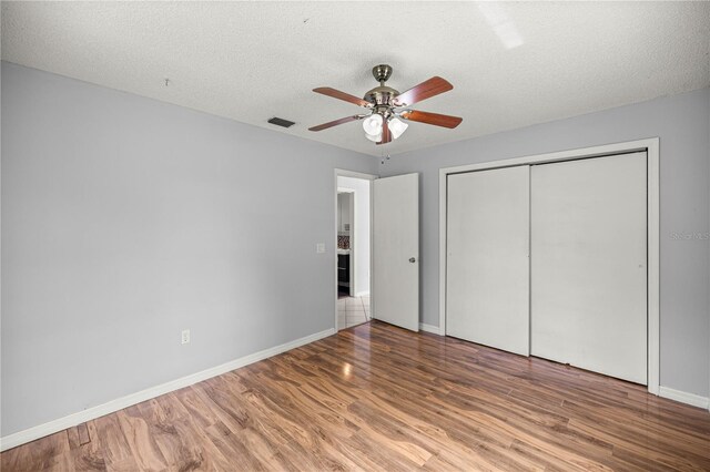 14171 SW 8th Ave, Ocala, FL 34473 - unfurnished bedroom with wood finished floors, a closet, a textured ceiling, and ceiling fan