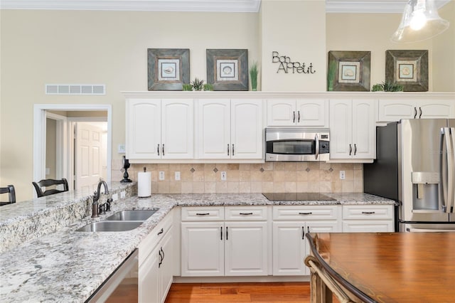kitchen featuring decorative backsplash, crown molding, a sink, visible vents, and stainless steel appliances