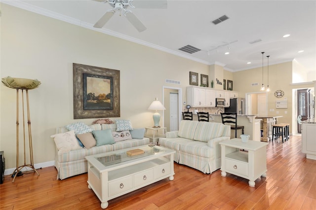 living area with track lighting, visible vents, ceiling fan, and crown molding